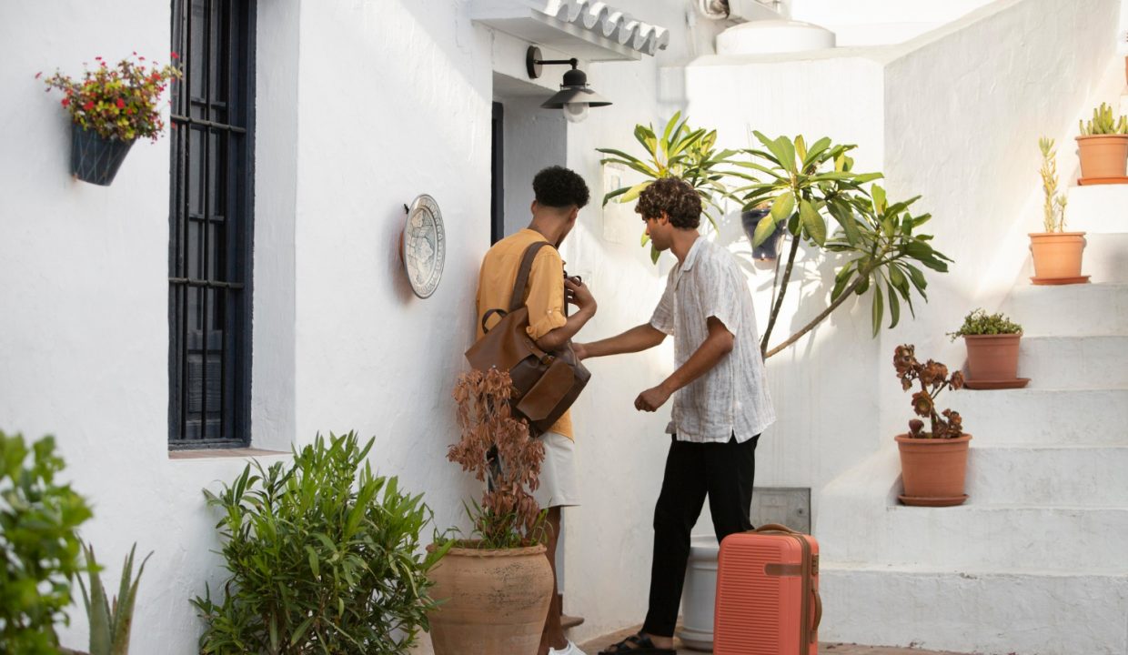 Un propriétaire accueille un voyageur avec un sourire chaleureux dans son logement.